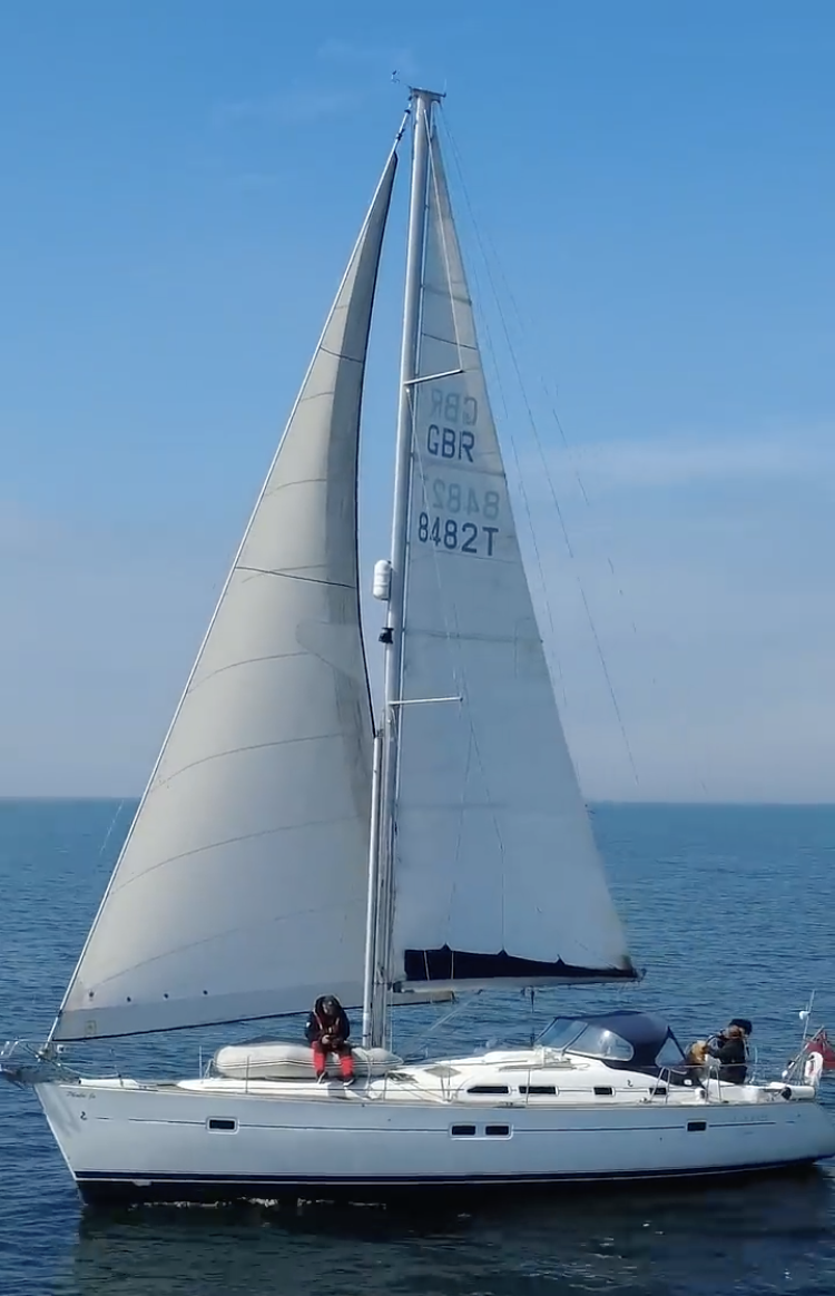 Phoebe Jo under full sail on a bright blue sea, with her whole rig and hull in view